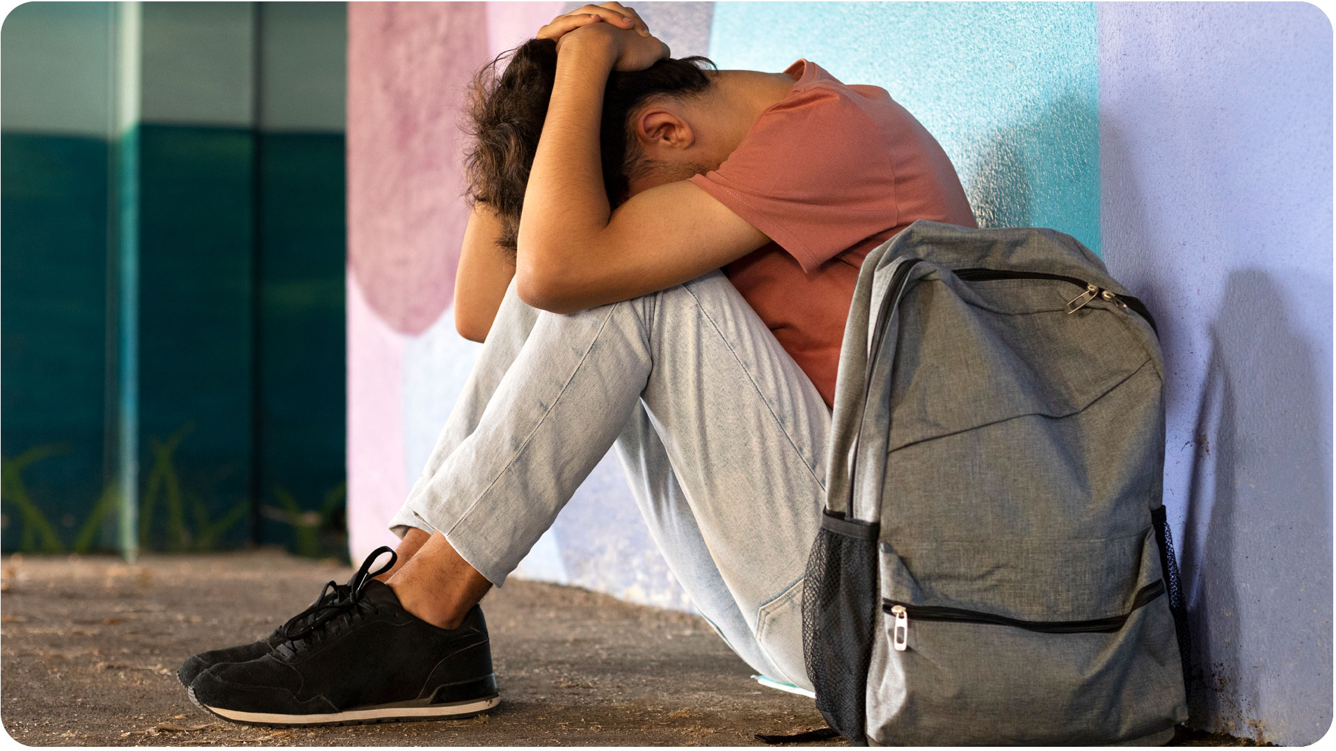 Um adolescente está sentado no chão com as pernas dobradas e está segurando a cabeça. Quase uma posição fetal, mas sentado. Essa imagem reforça a importancia da Campanha Setembro Amarelo